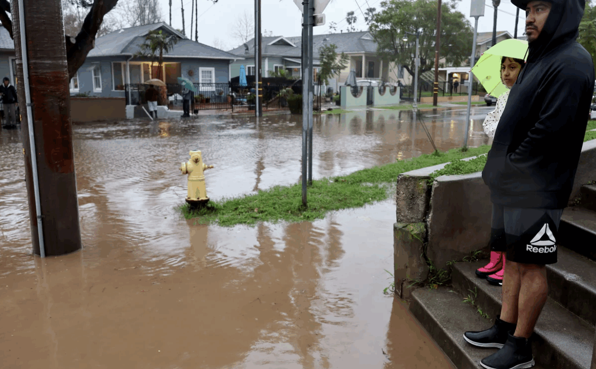 Residents stand along a flooded street in Santa Barbara, California, as a powerful atmospheric river pummels the region. The storm has caused landslides, power outages, and road and airport closures across Southern California. Mario Tama/Getty Images
